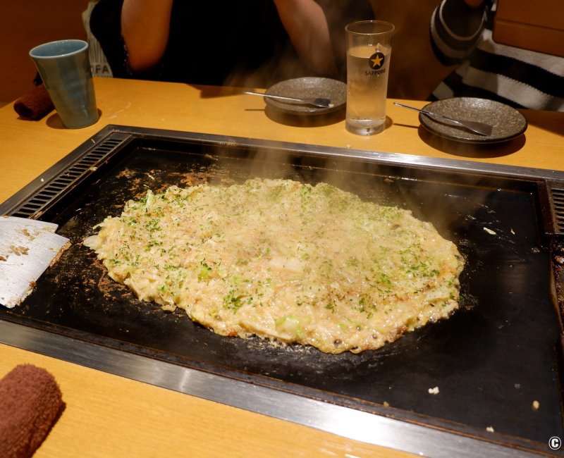 Okonomiyaki en train de cuire sur une plaque dans un restaurant du complexe Edo NOREN à Ryogoku (Tokyo) Okonomiyaki en train de cuire sur une plaque dans un restaurant du complexe Edo NOREN à Ryogoku (Tokyo)