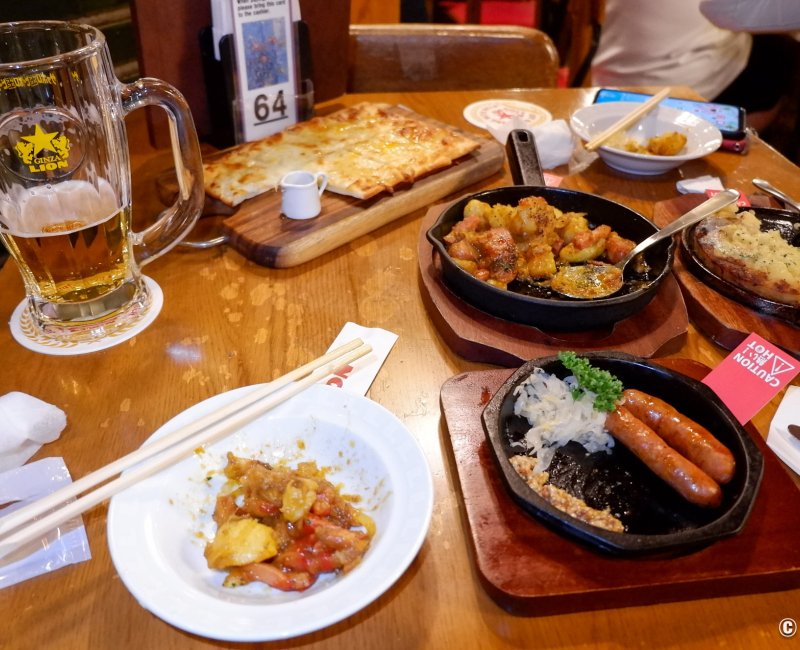 Ginza Lion 7-chome (Tokyo), sélection de plats (saucisses, curry de pommes de terre, flammekueche) avec de la bière Sapporo