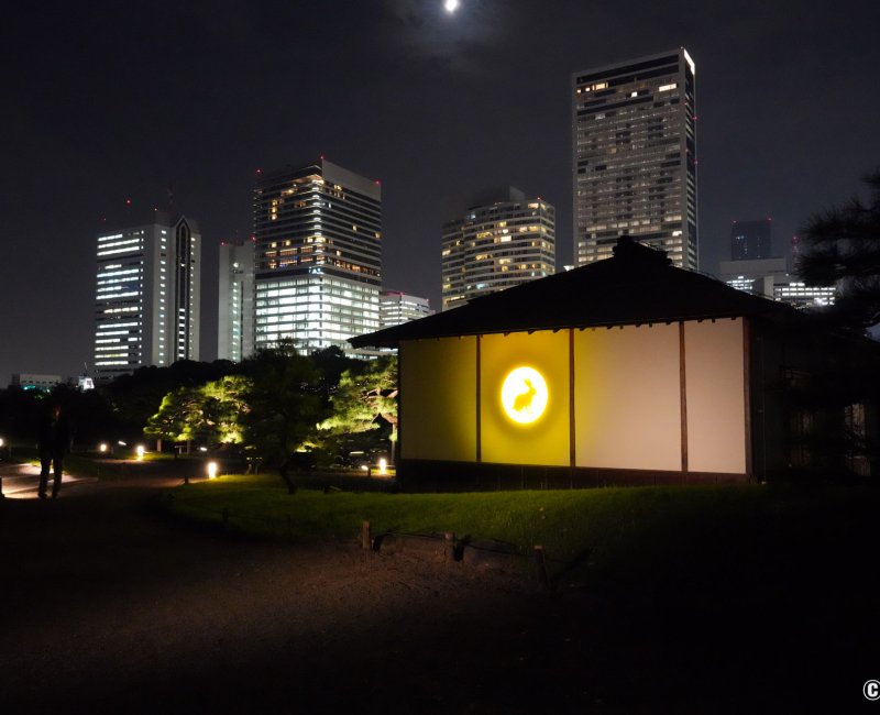 Hamarikyu Tsukimi Sanpo (Tokyo), façade du pavillon de thé Tsubame-no-Ochaya éclairée par une lune dorée avec un lapin