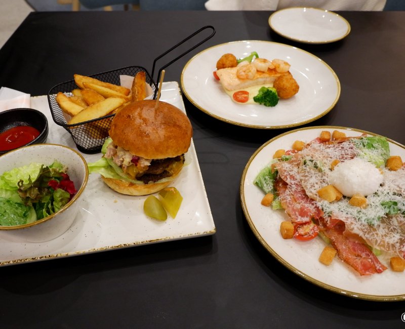 YOTEL Tokyo Ginza (Shinbashi), assiettes de cheeseburger au bœuf Wagyu, salade caesar prosciutto et saumon grillé du restaurant Komyuniti