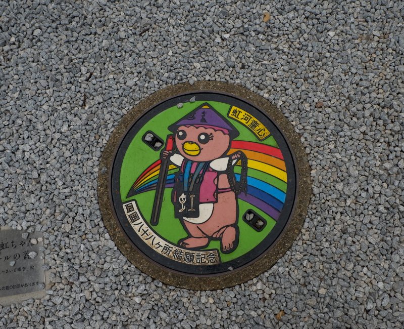 Pèlerinage de Shikoku, plaque d'égout de la mascotte en pèlerin au Chikurin-ji (31e temple) Pèlerinage de Shikoku, plaque d'égout de la mascotte en pèlerin au Chikurin-ji (31e temple)