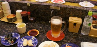 Thé vert à volonté et bière pour accompagner les sushis dans un Kaiten-zushi