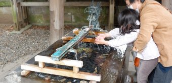 Hikawa-jinja (Kawagoe), enfant et adulte au bord du bassin pour les ablutions Chozuya en période de Covid