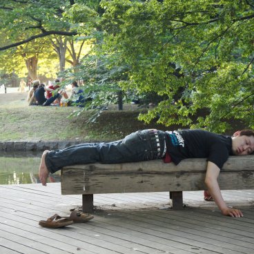 Parc Yoyogi à Tokyo, Homme endormi sur un banc de bois