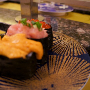 Gunkan-maki à l'oursin, negitoro et œufs de saumon servis dans un restaurant de kaiten-zushi