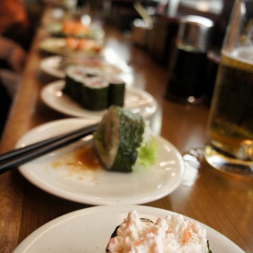 Défilé d'assiettes de sushis et mais dans un restaurant de kaiten-zushi