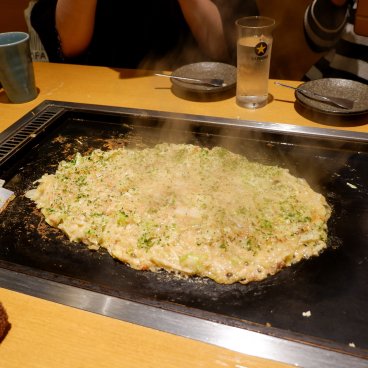 Okonomiyaki en train de cuire sur une plaque dans un restaurant du complexe Edo NOREN à Ryogoku (Tokyo)