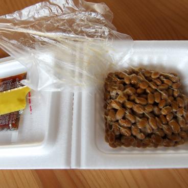 Barquette de natto ouverte avec les graines de soja et les assaisonnements 