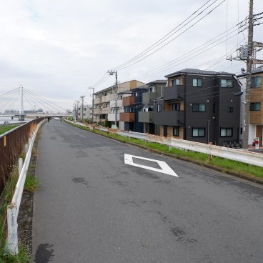 Ici Japon Village (Tokyo), vue sur les 2 maisons-hôtels depuis la piste cyclable le long de la rivière