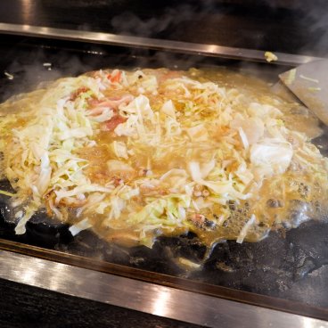 Tsukishima Monja Street (Tokyo), monjayaki en train de cuire sur une plaque dans un restaurant