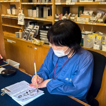 Photo autorisée par le temple Kencho-ji de la préposée aux goshuin en cours de calligraphie