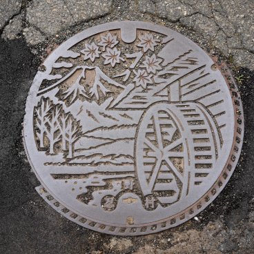 Oshino Hakkai (Fujiyoshida), Plaque d'égout représentant le Mont Fuji, des feuilles de momiji et une roue à aube